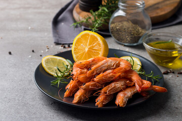 Shrimps on stone background. Grilled prawns with rosemary and lemon. 