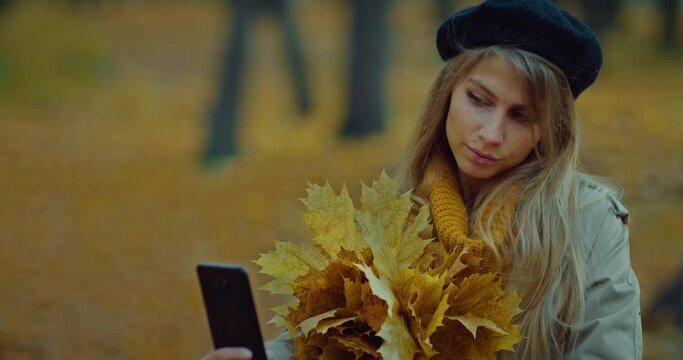 beautiful woman taking selfie in autumn forest, portrait with yellowed leaves bunch, 4K, Prores