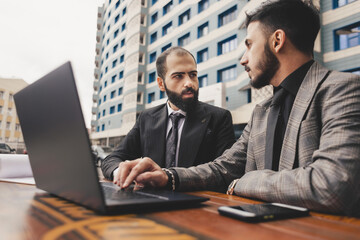 business people meets outdoors. Two men are using a laptop. Working break. Team and business support. Collaboration and partnership