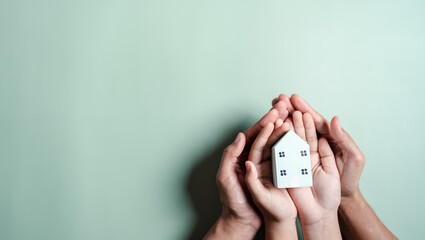 Hands holding wooden house, family home, homeless housing, mortgage crisis and home protecting insurance, international day of families, foster home care, family day care, stay home concept