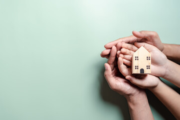 Hands holding wooden house, family home, homeless housing, mortgage crisis and home protecting...