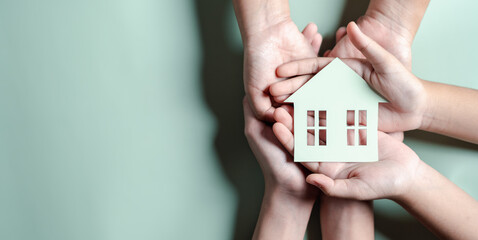 Hands holding wooden house, family home, homeless housing, mortgage crisis and home protecting insurance, international day of families, foster home care, family day care, stay home concept