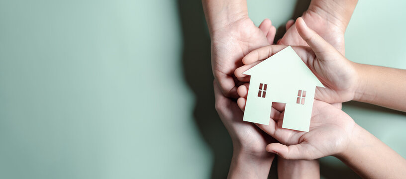 Hands holding wooden house, family home, homeless housing, mortgage crisis and home protecting insurance, international day of families, foster home care, family day care, stay home concept