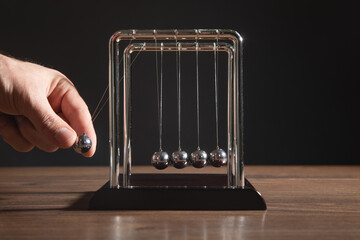 Male hand showing Newton's cradle balls. Business