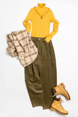 Female winter or autumn stylish clothing set. Plaid checkered shirt, yellow sweater and leather boots, green corduroy trousers, accessories. Trendy fashionable casual clothes. Fashion concept