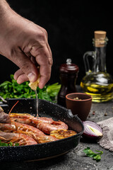 Grilled tiger shrimps with spice, lemon and garlic in a frying pan on a dark background. Prawns fried, Seafood appetizer vertical image. top view