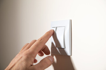 Male hand turning off or on light switch.