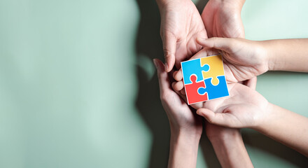 Color puzzle symbol of awareness for autism spectrum disorder family support. Father, Mother, Children holding jigsaw puzzle Autism World Awareness Day.