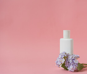 Obraz na płótnie Canvas Mockup cosmétique sur fond rose avec fleur mauve