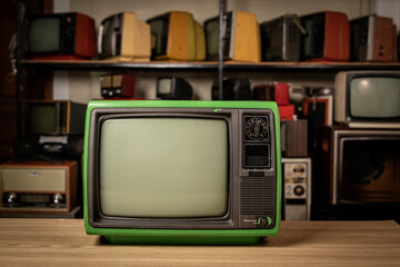 Green old retro television on table with TVs shelf in room