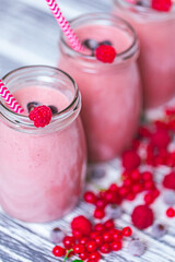 Three jars with yogurt smoothie with cranberry, raspberry, blueberry on wood table. Selective focus