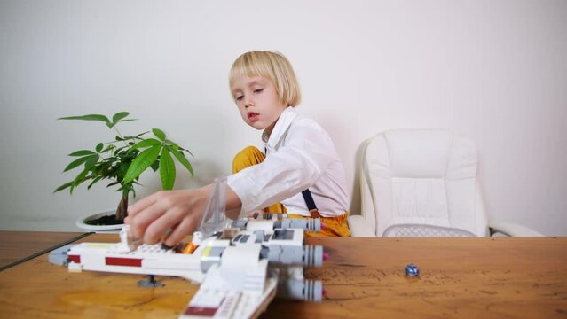 5 years old boy plays with Star Wars spaceship from constructor at home adjusting details to it. It is a vessel designed for interstellar travel, specifically between star systems