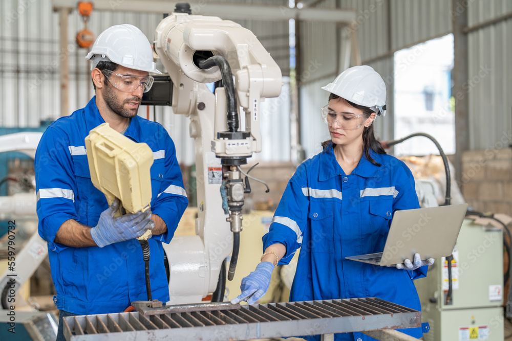 Wall mural male and female engineer training using remote controller control robot arm welding machine in indus