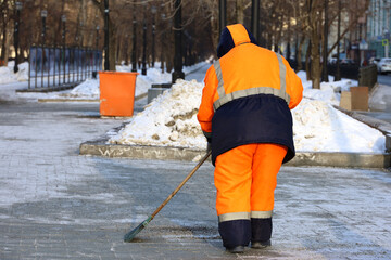Cleaning street in winter city, woman janitor with broom removes snow in park. Work of communal...