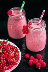 Two jars with yogurt smoothie with cranberry, raspberry on black background. Selective focus 