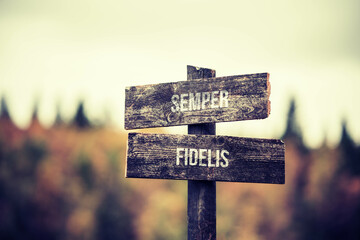 vintage and rustic wooden signpost with the weathered text quote semper fidelis, outdoors in...