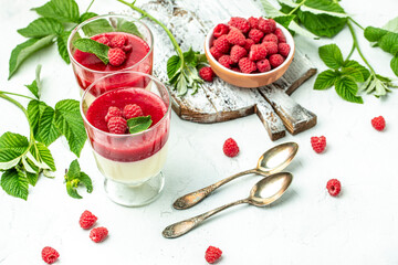 Raspberry Panna cotta with raspberry jelly on a light background. Berry dessert with cream sauce in small jars. place for text