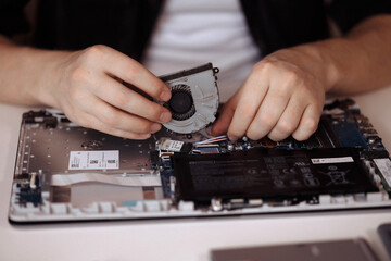 Disassembling a laptop with a screwdriver in a repair shop. 