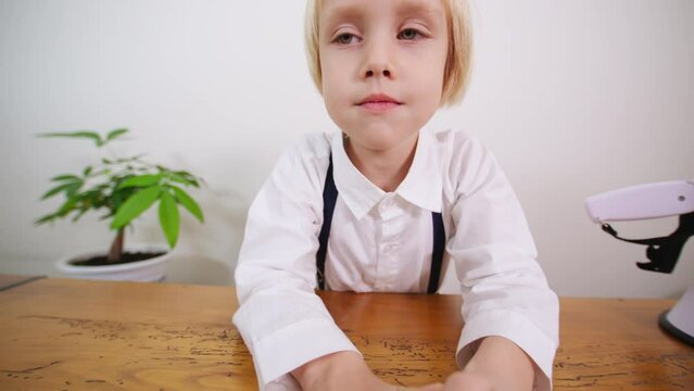 Close portrait of 5 years old caucasian boy making funny faces into the camera. A boy with fair hair and blue eyes smiles into the camera showing teeth