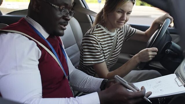 Driving school concept video. A car instructor teaches a young woman how to drive. Teaching the rules of the road and driving a vehicle