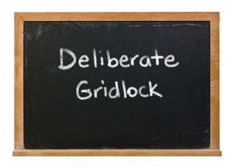 Deliberate gridlock written in white chalk on a black chalkboard isolated on white