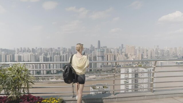 Caucasian Blond-Haired Women Standing and Taking Stunning Cityscape Picture with Her Cell Phone, Asian Mega City View, Chinese City Landscape 4K Footage. 