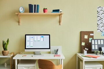 Background image of minimal office setup with computer screen and planning charts against pastel yellow wall, copy space
