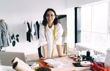 Cheerful ethnic woman with measuring tape in modern studio