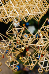 Closeup of authentic handmade straw ornament with Christmas light and tree on the background
