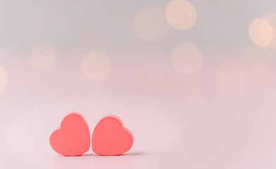 Two hearts against a pink background with blurry lights.