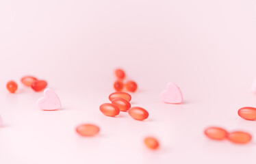 Red pills with pink hearts on light background.