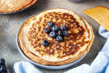 a stack of pancakes with blueberries on the table, hearty breakfast