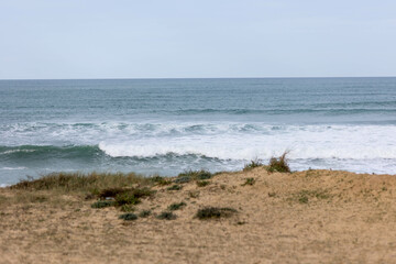 Photographie d'une plage avec au premier plan la dune est au second plan l'océan et des vagues et au troisième plan le ciel