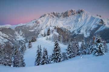 Sunrise in the mountains Winter landscape with snowy peaks and trees, Italian Alps, Lombardy, Italy.