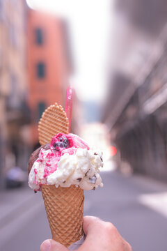 Hand holding colorful mixed italian ice cream in a fresh waffle. Vertical close-up.