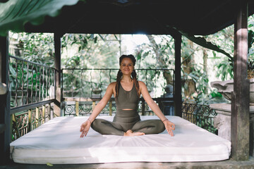 Smiling sportswoman meditating in lotus pose