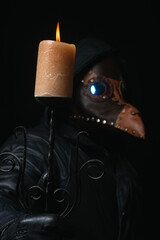 Plague doctor with crow-like mask and candle isolated on black background Creepy halloween historical terrible costume concept Epidemic covid smallpox monkeypox