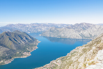 Obraz premium Panoramic view from Derinski Vrh (Pestingrad) of Kotor bay on sunny summer day, Adriatic Mediterranean Sea, Montenegro, Balkan, Europe. Fjord winding along coastal towns. Lovcen, Orjen mountain range