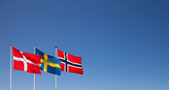 D&auml;nische, Schwedische und Norwegische Nationalflagg im Wind wehend vor blauem Himmel