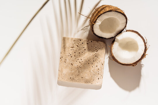 Cosmetic product presentation scene made with travertine tile mockup podium and coconuts.