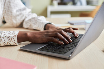 Close up of unrecognizable black young woman using laptop and typing on keyboard