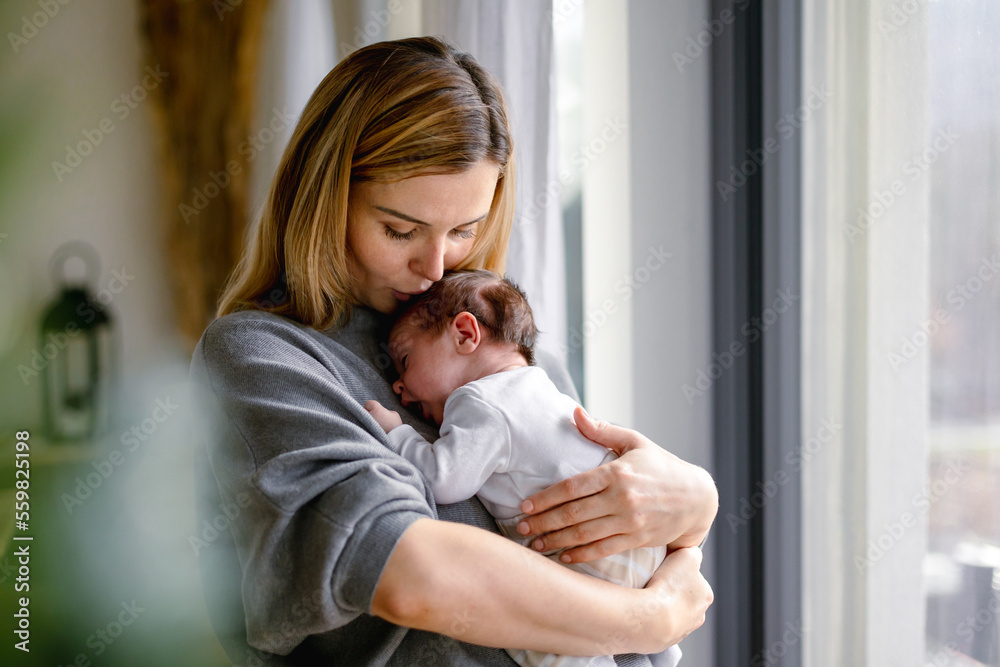 Wall mural loving mother hugs her little baby at home