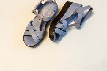 Blue sandals on light background. Stylish summer women's leather shoes, top view, copy space