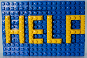 The word "help" is lined with a children's colored plastic constructor.