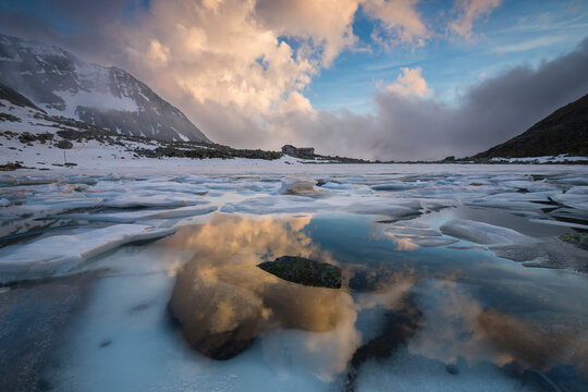 Alpine lake thaw near Tonolini refuge in a high mountain landscape during spring season, Italian Alps, Lombardy, Italy.