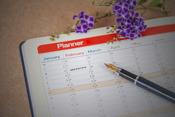 word wedding on calendar with sweet flowers and pen ,love concept.