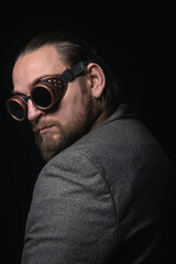 charismatic man in a classic suit and steampunk goggles on a black background stylish Portrait
