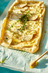 Homemade savory square pie with pears, blue cheese and honey on blue background, sunlight. Copy space. Delicious baked food.