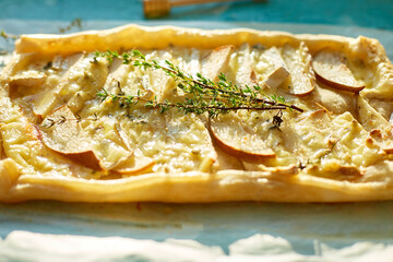 Homemade savory square pie with pears, blue cheese and honey on blue background, sunlight. Copy space. Delicious baked food.