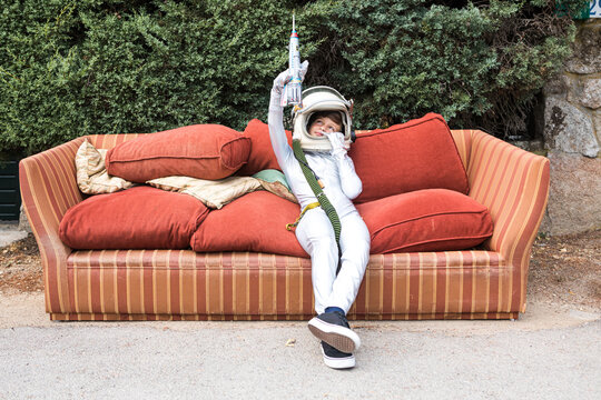 Child in space suit shooting gun on sofa on street